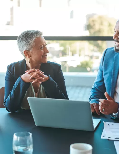 Man and woman sitting at a table, discussing work and collaborating.